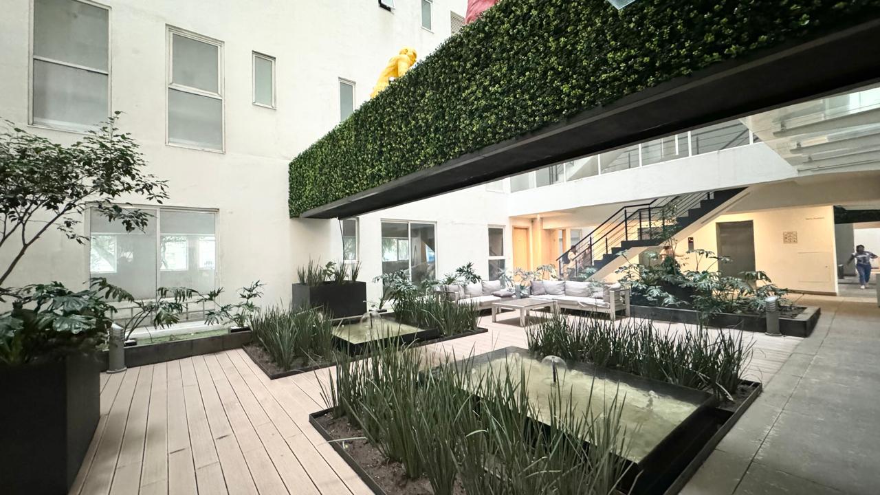 Patio interior con muros verdes, espejos de agua y sala exterior
