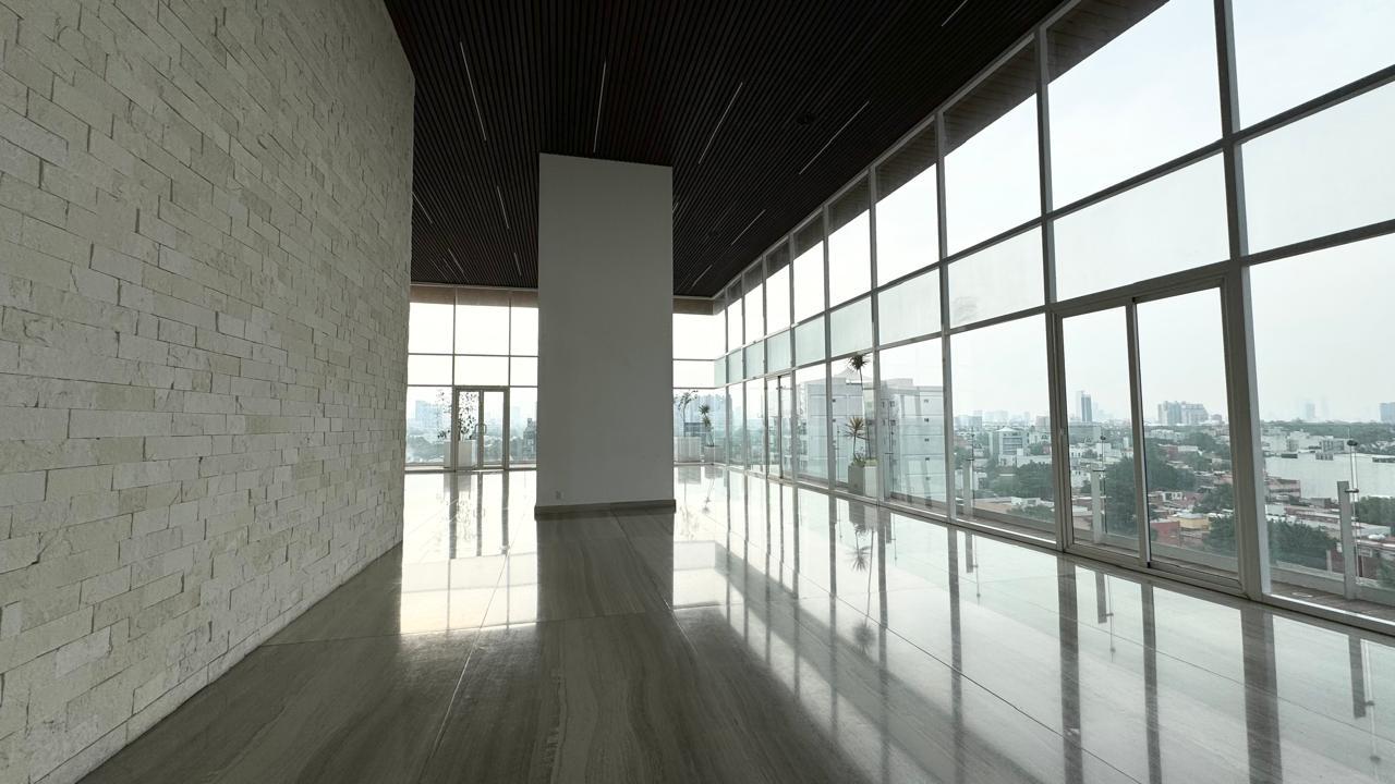 Salón con muro de piedra y ventanales de piso a techo con vista a la ciudad