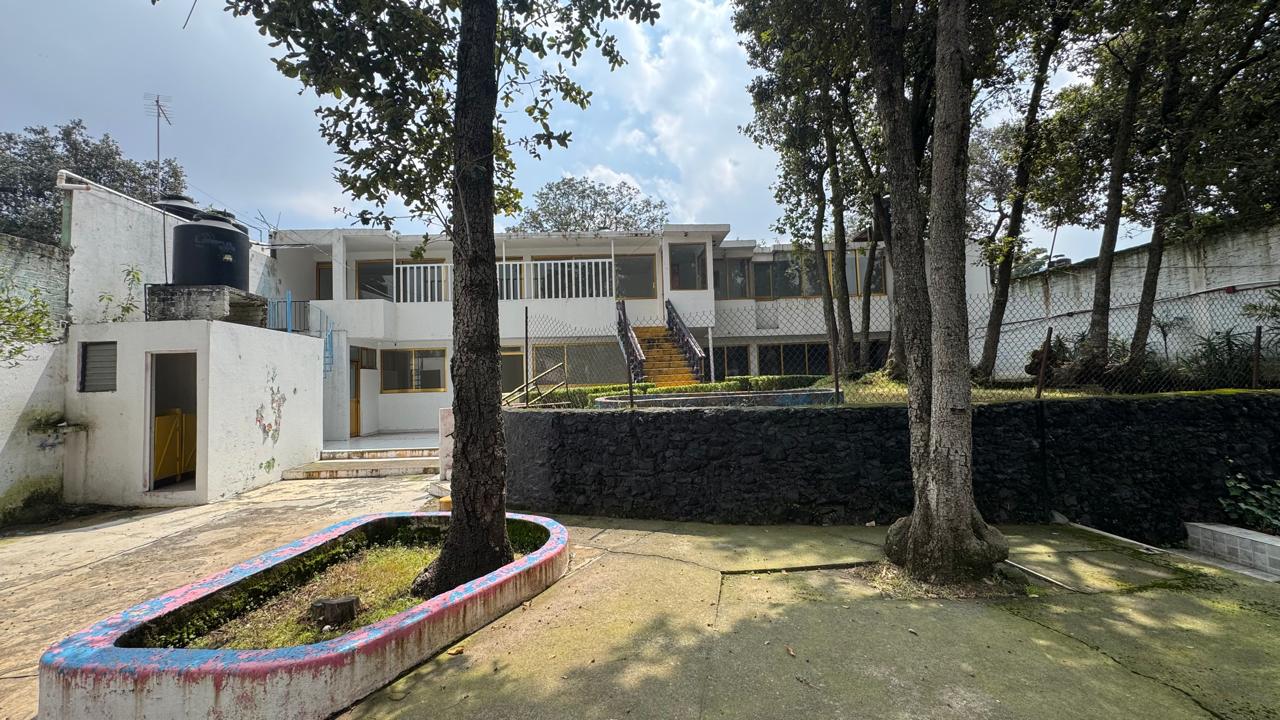 Vista del patio principal con arbolado y construcción de dos niveles