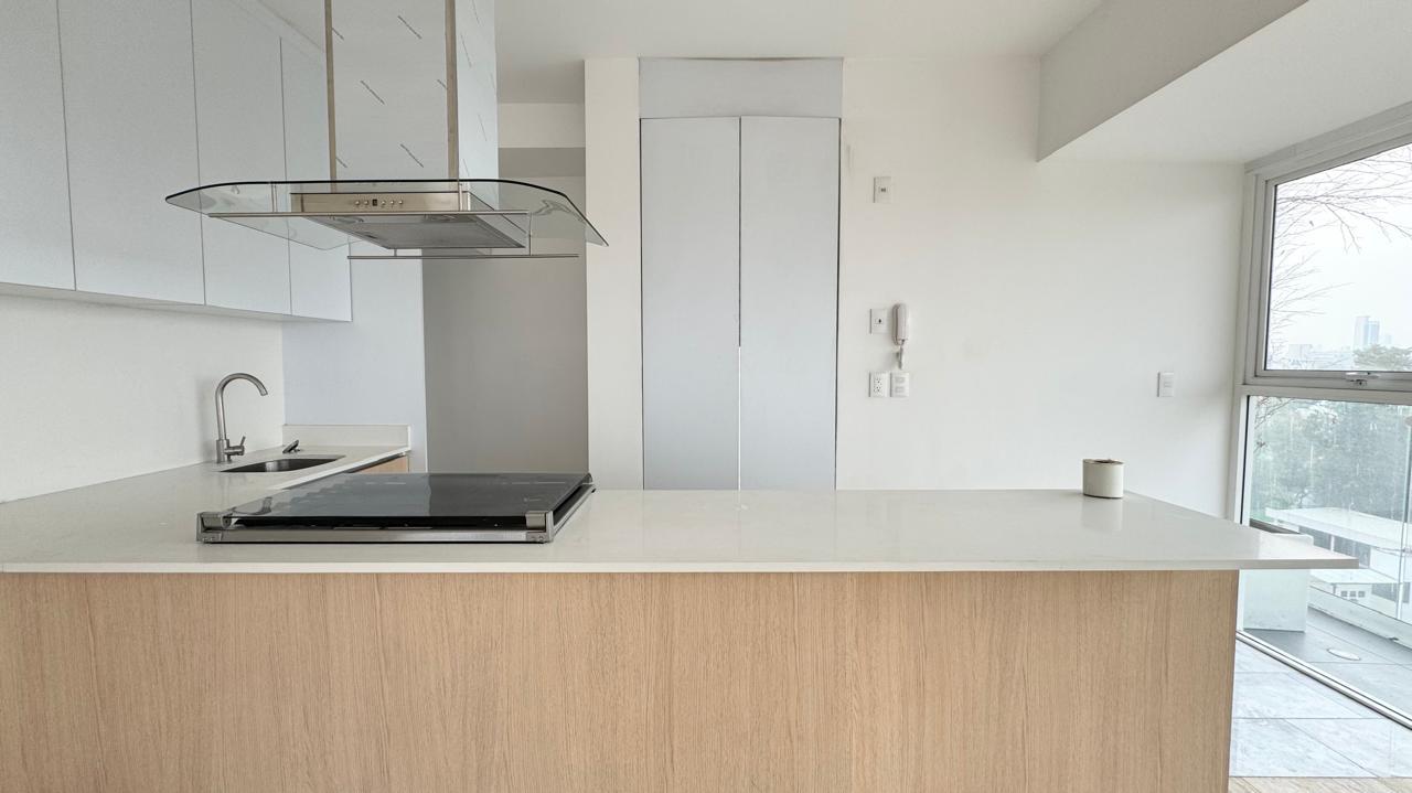 Cocina integral abierta con campana de cristal y barra de cuarzo