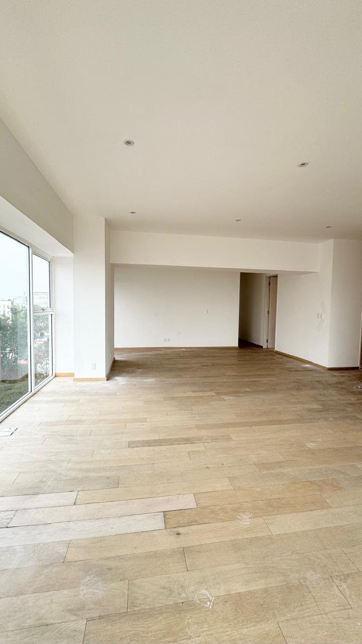 Estancia amplia con piso de madera y ventanal al exterior