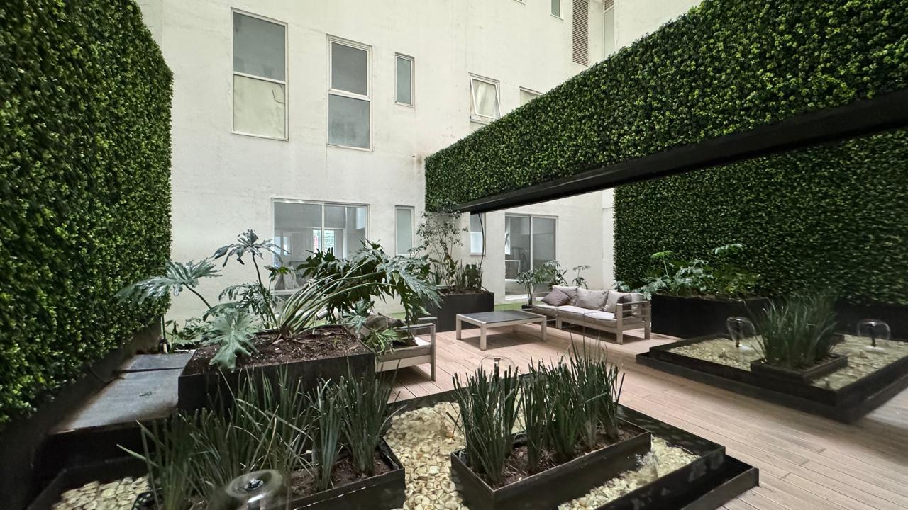Terraza jardín con muros verdes y mobiliario exterior