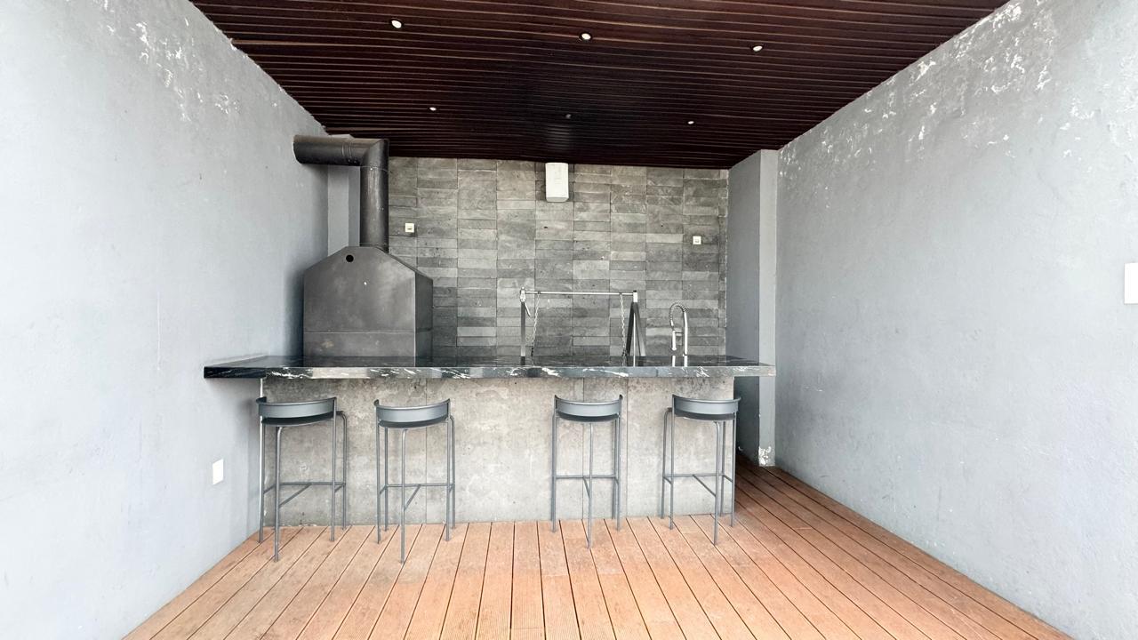 Área de grill con barra, asador y bancos altos